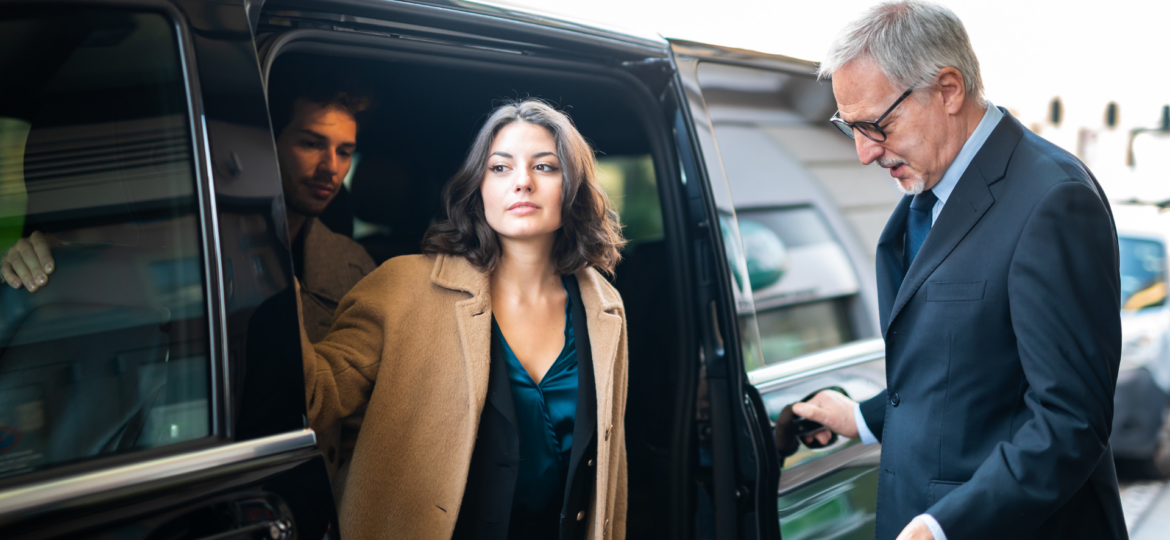 A professional woman stepping out of a sleek employee shuttling car, showcasing Dream Limousines' reliable shuttle rental service for corporate events and employee transportation.