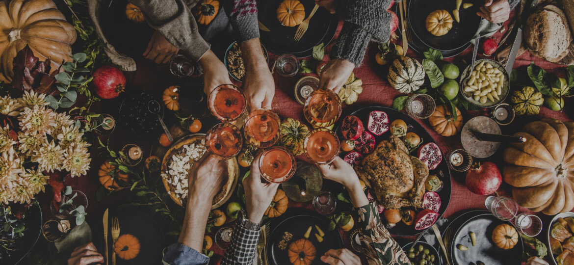 A-group-of-friends-celebrating-Friendsgiving,-raising-their-glasses-and-enjoying-a-potluck-feast-on-a-party-bus-in-Detroit