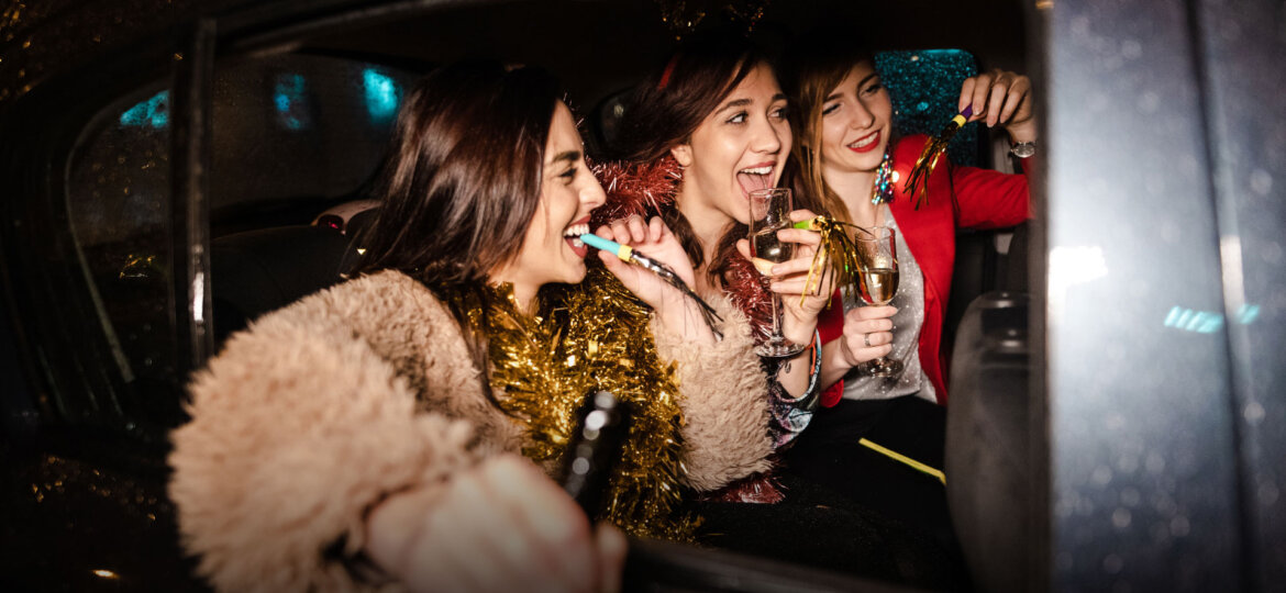 A group of friends laughing and clinking glasses inside a luxurious Dream Limousines vehicle, featuring plush leather seating and ambient lighting.