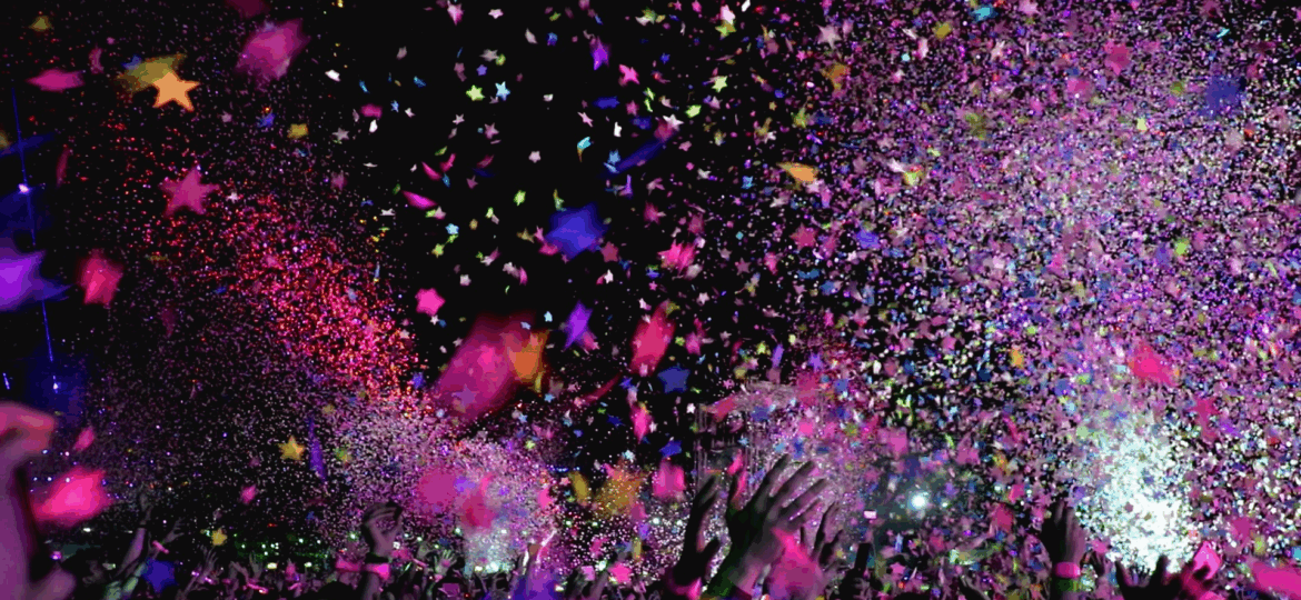 Confetti in the air with people's hands up at a Detroit concert with transportation provided by Dream Limousine.