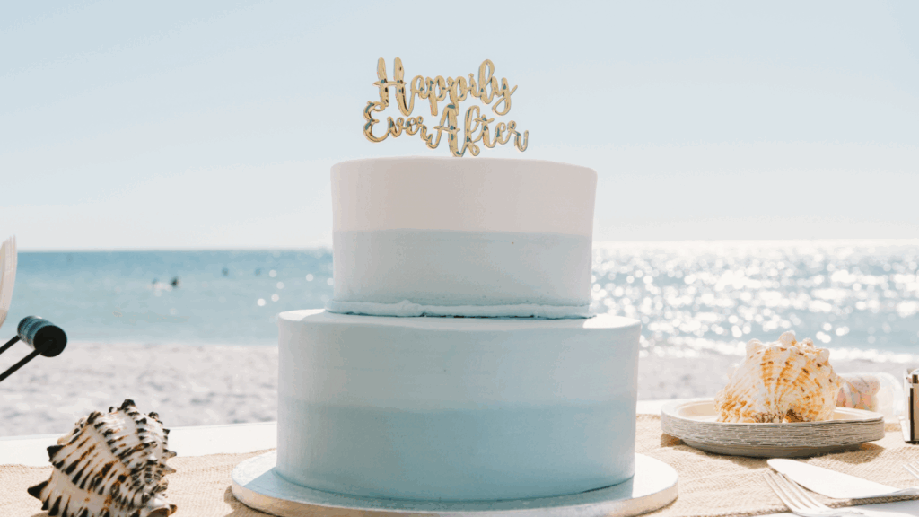 A cake on a table in front of a beach view matching a coastal minimalism wedding theme, awaiting arrival from the wedding shuttle service.