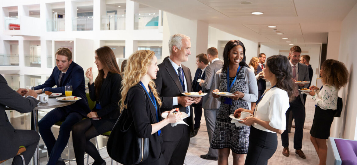 Professionals mingle over food at a corporate event.